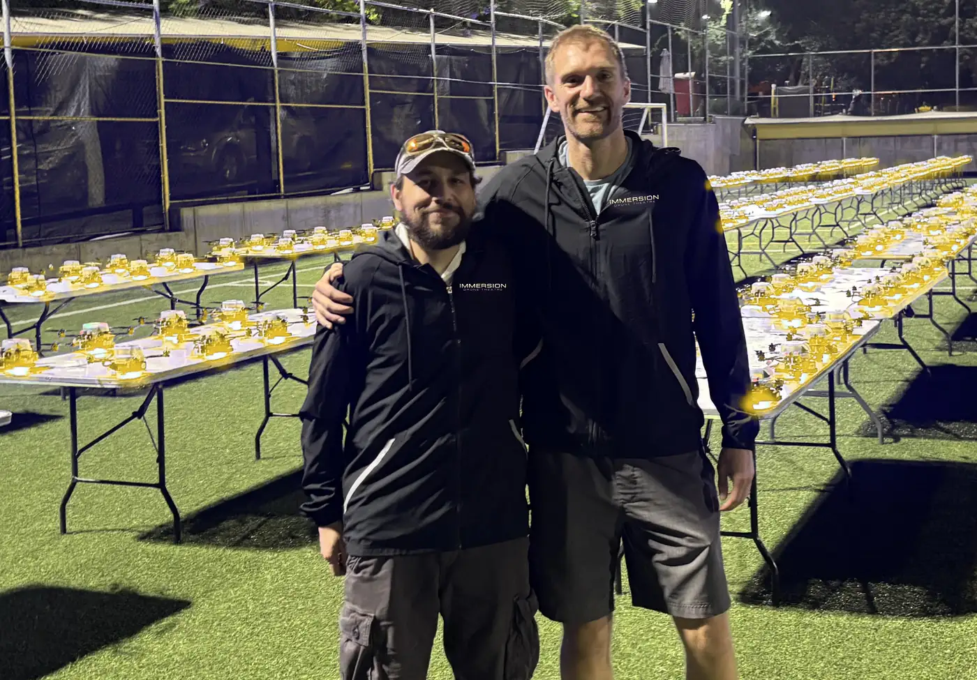 Immersion Drone Theatre founder Jamison Russell and lead engineer Mark Huff II standing before their drone light show fleet staged for takeoff at night