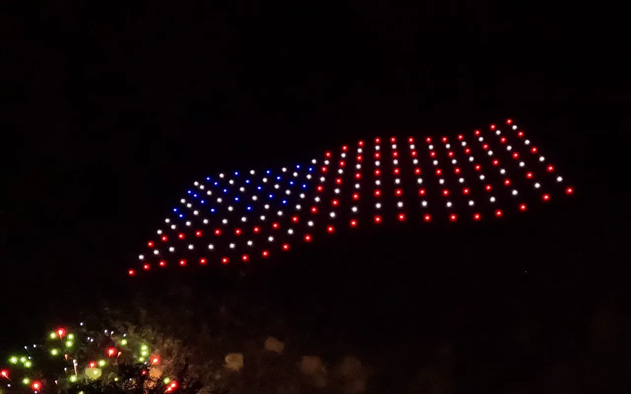 A drone light show forms an American flag above a crowd at night. Immersion produces drone light shows in Colorado Springs, Colorado.