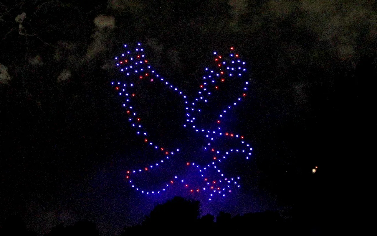 A drone light show forms a dove in blue and red against the night sky. Immersion produces drone light shows in Fort Collins, Colorado.