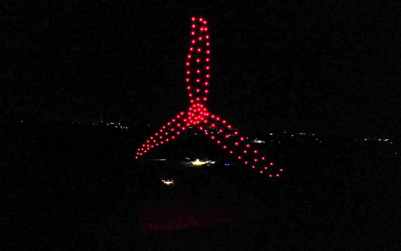 A drone light show forms a three-blade propeller in red against the night sky. Immersion produces drone light shows in Hartford, Connecticut.