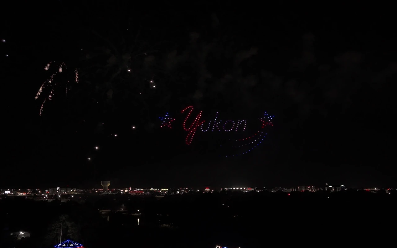 A drone light show forms the word Yukon in glowing script over the community at night.