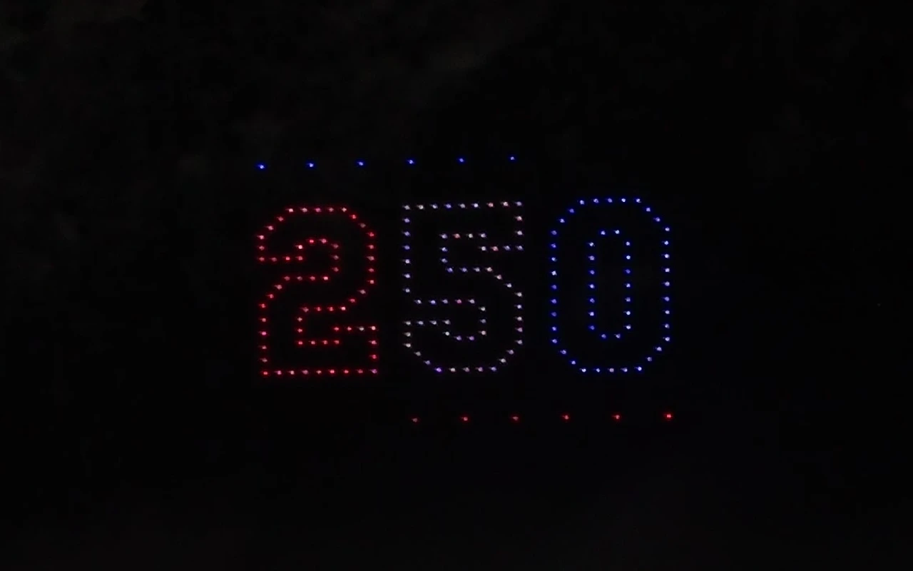 A drone light show forms the number 250 in red, white, and blue for America's 250th, above the crowd.