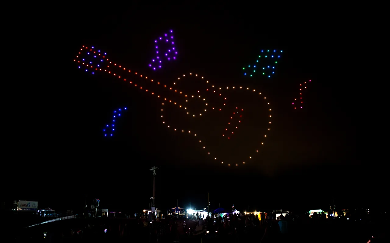A drone light show forms a guitar above the horizon at night. Immersion produces drone light shows in Salt Lake City, Utah.